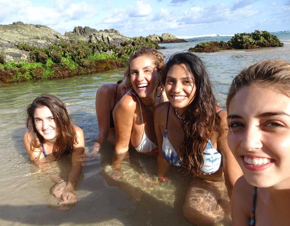 grupo de chicas en bikini y en el agua sonriendo y posando para cámara